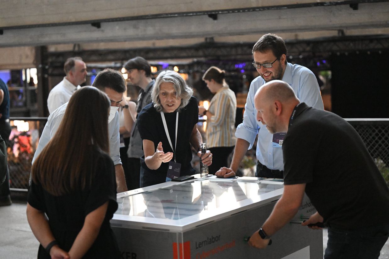 Five people play &quot;cyberkicker&quot; on a virtual foosball table